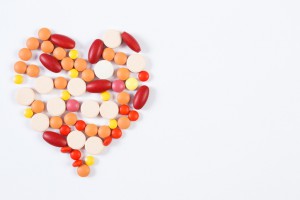 Heart shaped medical pills and capsules on white background
